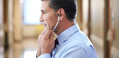 Docteur plaçant correctement son stéthoscope Littmann (embouts auriculaires vers l’avant).
